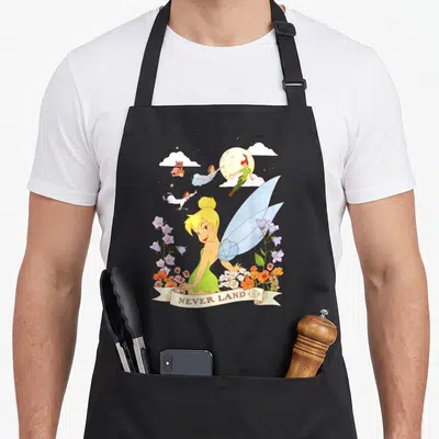 Tablier de cuisine noir avec Tinker Bell, Peter Pan et l'inscription Never Land entourés de fleurs colorées.