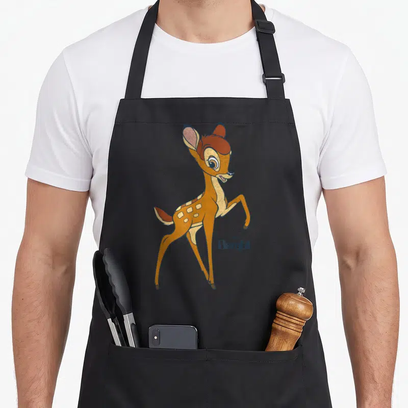 Tablier de cuisine noir avec illustration colorée de Bambi debout et le logoDisney en bas à droite.