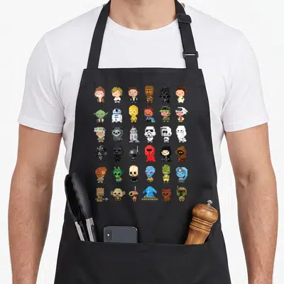 Tablier de cuisine noir avec une grille de personnages Star Wars stylisés en art pixelisé 8-bit coloré.