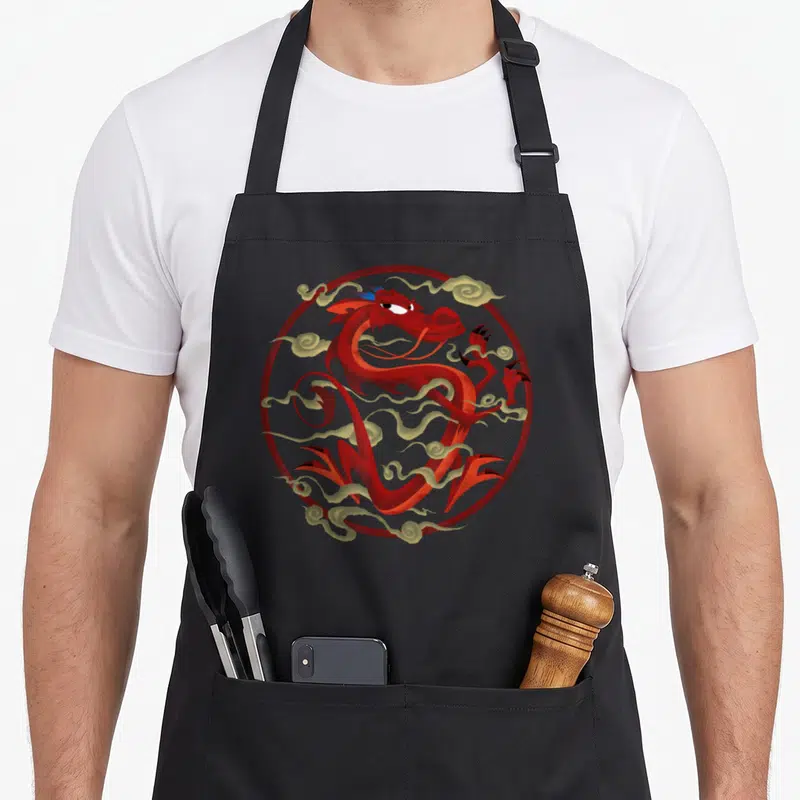 Tablier de cuisine noir avec un dragon rouge stylisé Mushu entouré de nuages dorés dans un cercle.