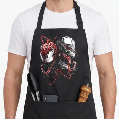 Tablier de cuisine noir avec illustration métallique rouge et argent de deux têtes de monstres aux expressions féroces et aux tentacules fluides.