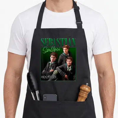 Tablier de cuisine noir avec le portrait de Sebastian Sallow et le logo Hogwarts Legacy en vert sur fond sombre.
