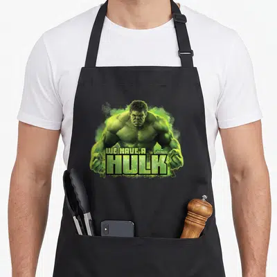 Tablier de cuisine noir avec une illustration verte du Hulk et le texte We Have A Hulk en grosses lettres.