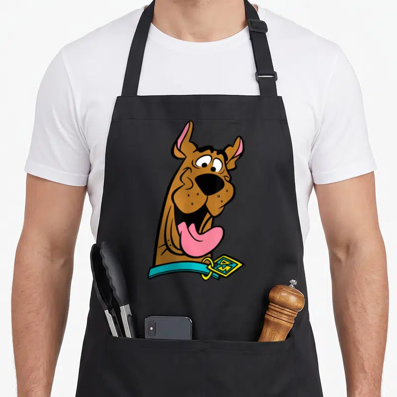 Tablier de cuisine noir avec illustration colorée de Scooby-Doo souriant largement et sa langue rose pendante.