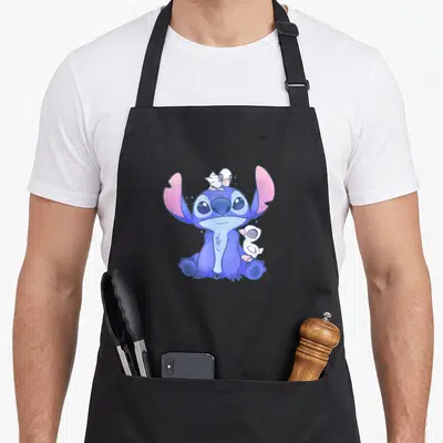Tablier de cuisine noir avec Stitch bleu et trois canetons blancs posés sur sa tête et son épaule.