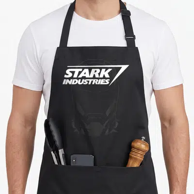 Tablier de cuisine noir avec le logo Stark Industries et l'illustration du casque d'Iron Man en dessin au trait blanc.