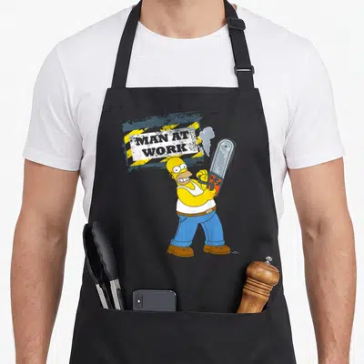 Tablier de cuisine noir avec Homer Simpson tenant une tronçonneuse sous un panneau Man at Work jaune et gris.
