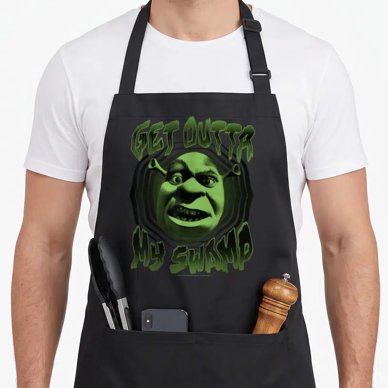 Tablier de cuisine noir avec visage vert de Shrek et texte Get Outta My Swamp en lettres stylisées.