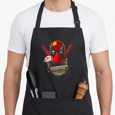 Tablier de cuisine noir avec le visage de Deadpool, deux katana croisés et une chaîne dorée portant l'inscription DEADPOOL.