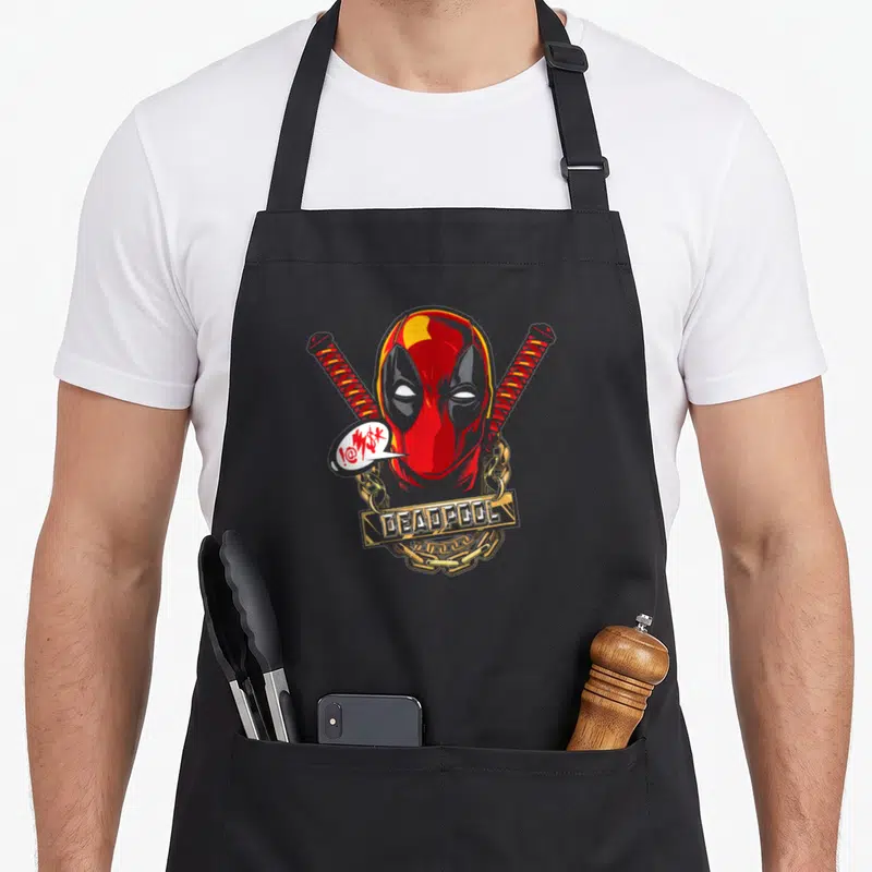Tablier de cuisine noir avec le visage de Deadpool, deux katana croisés et une chaîne dorée portant l'inscription DEADPOOL.