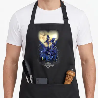Tablier de cuisine noir avec illustration de personnages dans un cœur lumineux et le logo stylisé en bas.