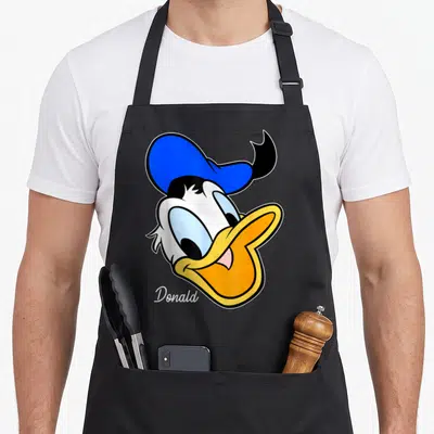 Tablier de cuisine noir avec un gros visage de Donald Duck au chapeau bleu et le nom Donald écrit en blanc.