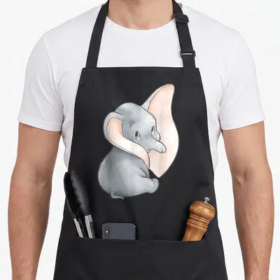 Tablier de cuisine noir avec portrait aquarellisé de Dumbo éléphant aux grandes oreilles roses et yeux bleus.