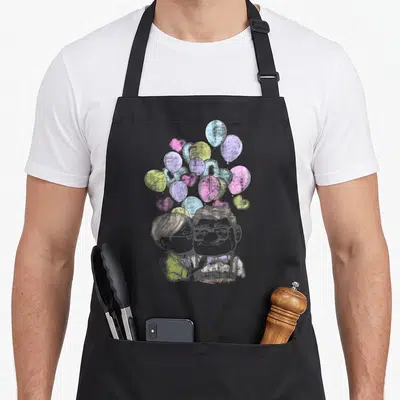 Tablier de cuisine noir avec illustration de Carl et Ellie Love sous des ballons pastel colorés.