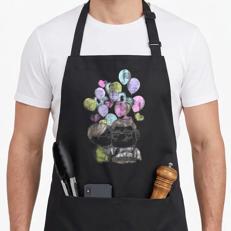 Tablier de cuisine noir avec illustration de Carl et Ellie Love sous des ballons pastel colorés.