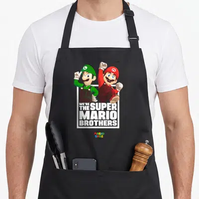 Tablier de cuisine noir avec Mario et Luigi en pose dynamique et le texte blanc We're The Super Mario Brothers.