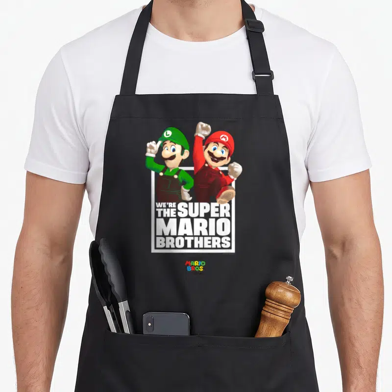 Tablier de cuisine noir avec Mario et Luigi en pose dynamique et le texte blanc We're The Super Mario Brothers.