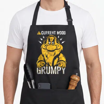 Tablier de cuisine noir avec illustration orange et blanche du nain Grumpy en train de se fâcher.