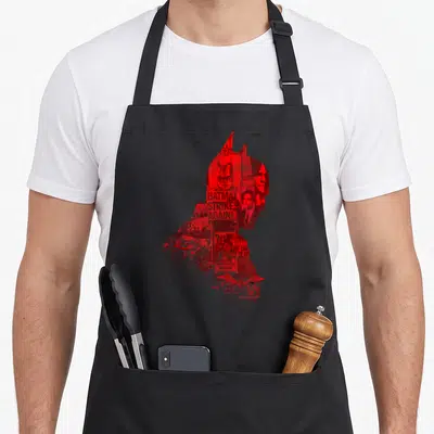 Tablier de cuisine noir avec une silhouette rouge de Batman constituée d'articles de presse et du texte BATMAN STRIKES AGAIN.