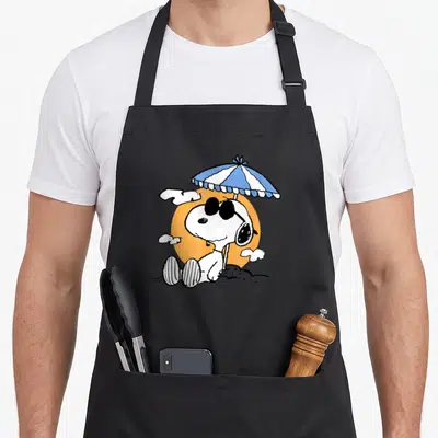 Tablier de cuisine noir avec Snoopy aux lunettes noires sous un parasol de plage.