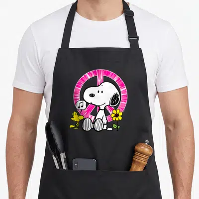 Tablier de cuisine noir avec Snoopy, Woodstock, une note de musique et un panneau de paix rose vif.