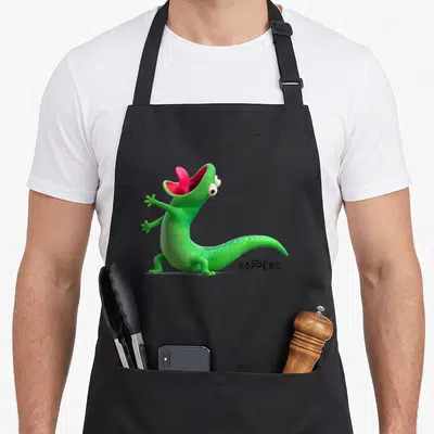 Tablier de cuisine noir avec un lézard vert criant et le titre Hoppers imprimé en noir.