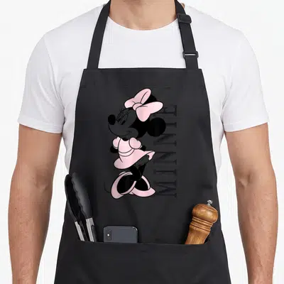 Tablier de cuisine noir avec illustration de Minnie Pink et texte MINNIE vertical en lettres noires.