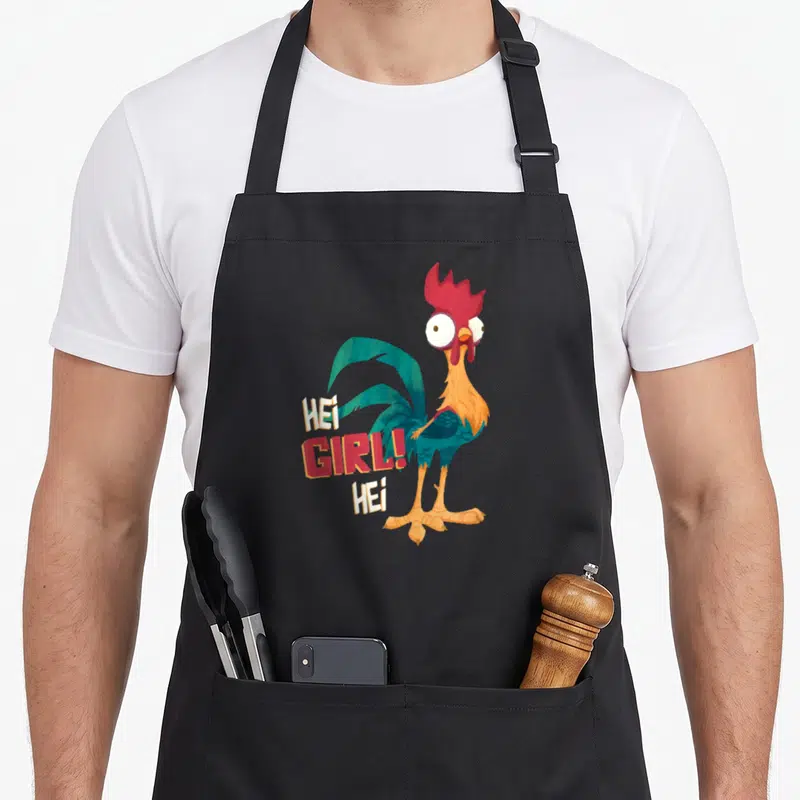 Tablier de cuisine noir avec illustration du coq Hei et du texte Hei Girl Hei en lettres colorées.