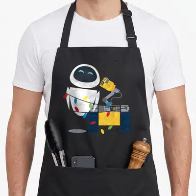 Tablier de cuisine noir avec Eve et Wall-E entourés de guirlandes lumineuses colorées.