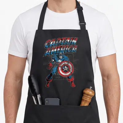 Tablier de cuisine noir avec illustration vintage Captain America tenant son bouclier circulaire.