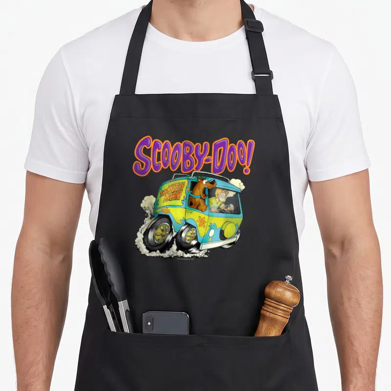 Tablier de cuisine noir avec Scooby-Doo, Shaggy et la Mystery Machine colorée imprimés sur le devant.