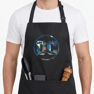 Tablier de cuisine noir avec logo DC Comics stylisé montrant Batman et Gotham City en bleu.