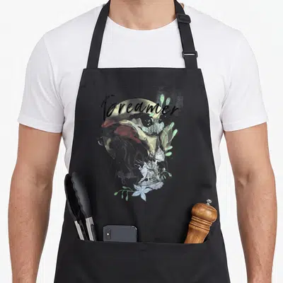 Tablier de cuisine noir avec une sirène en esquisse et le mot Dreamer au-dessus.
