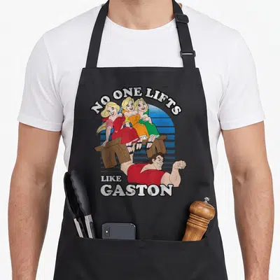 Tablier de cuisine noir avec illustration de Gaston portant un banc avec trois femmes et le texte No One Lifts Like Gaston.