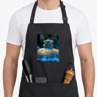 Tablier de cuisine noir avec Grogu assis en tailleur sur une roche entouré d'éclairs bleus et du logo Mandlorian.