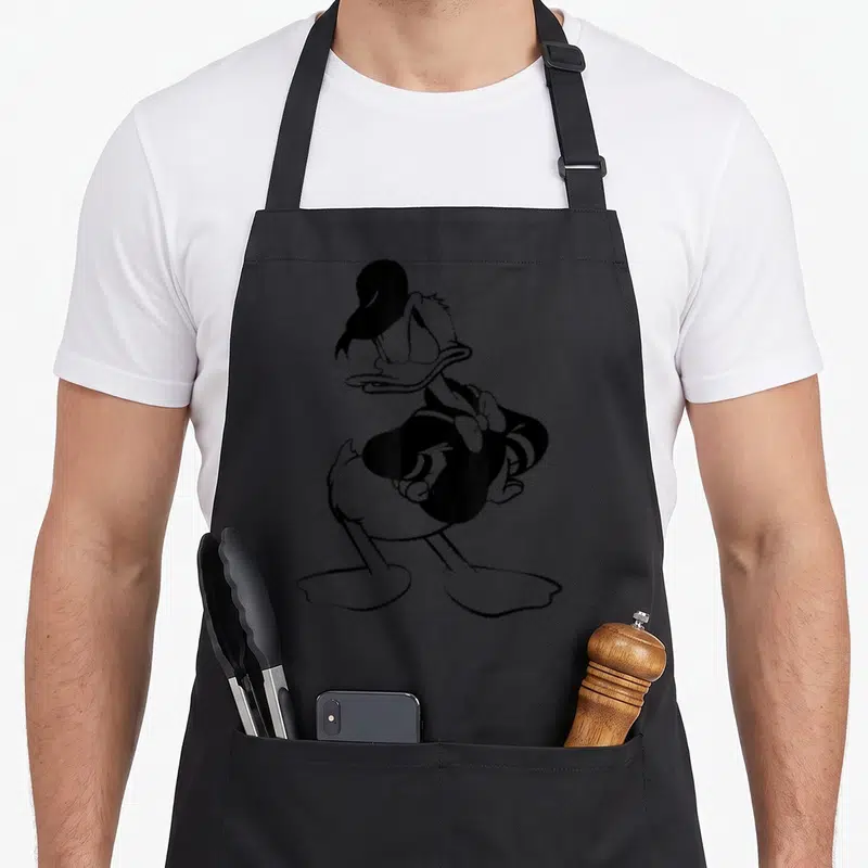 Tablier de cuisine noir avec illustration de Donald Duck en silhouette noire posant les mains sur les hanches