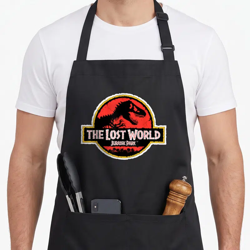 Tablier de cuisine noir avec logo circulaire rouge et noir The Lost World Jurassic Park représentant un dinosaure.