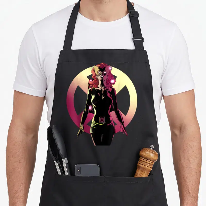 Tablier de cuisine noir avec une illustration colorée de Jean Grey en tenue noire devant un logo circulaire jaune et rose.