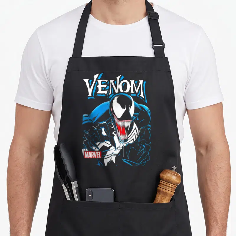 Tablier de cuisine noir avec illustration Venom blanc bleu rouge et logo Marvel en bas à gauche.
