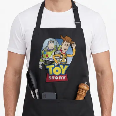 Tablier de cuisine noir avec Buzz Lightyear, Woody et le logo coloré Toy Story au centre.