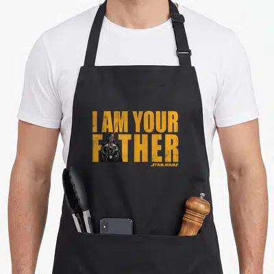 Tablier de cuisine noir avec l'illustration de Dark Vador et le texte I AM YOUR FATHER en lettres oranges.