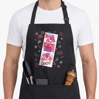 Tablier de cuisine noir avec une bande photo rose de Lotso et des croquis d'objets d'enfants en arrière-plan.
