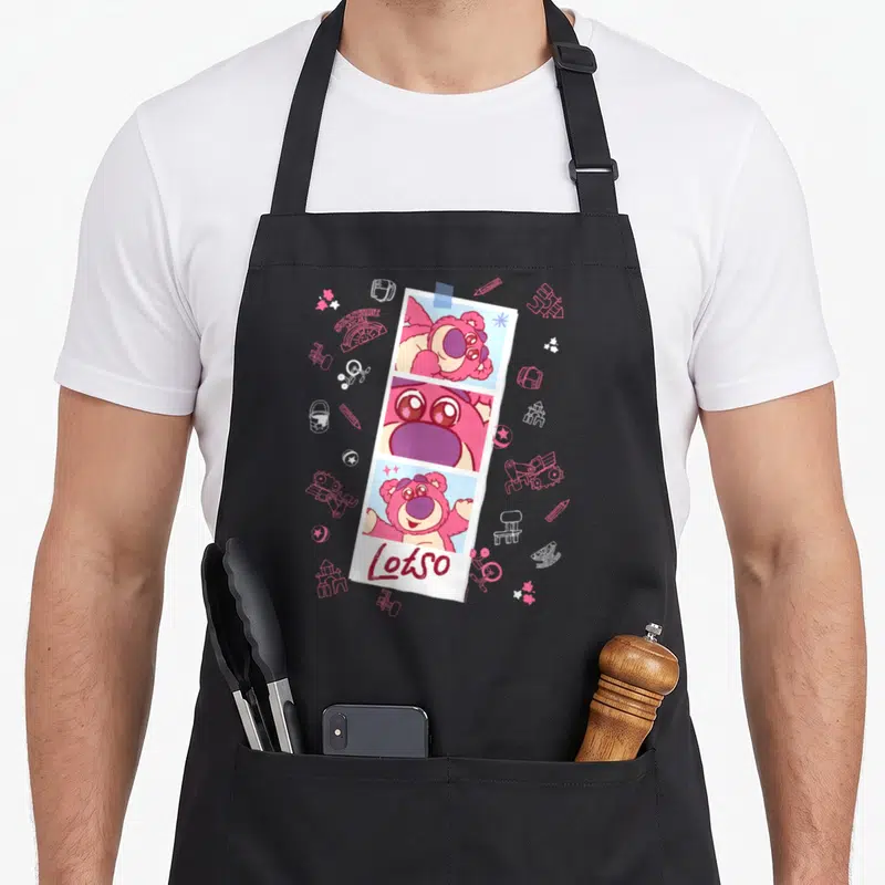 Tablier de cuisine noir avec une bande photo rose de Lotso et des croquis d'objets d'enfants en arrière-plan.