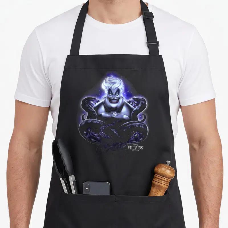 Tablier de cuisine noir avec portrait stylisé d'Ursula aux tentacules et inscription Villains en bas à droite.