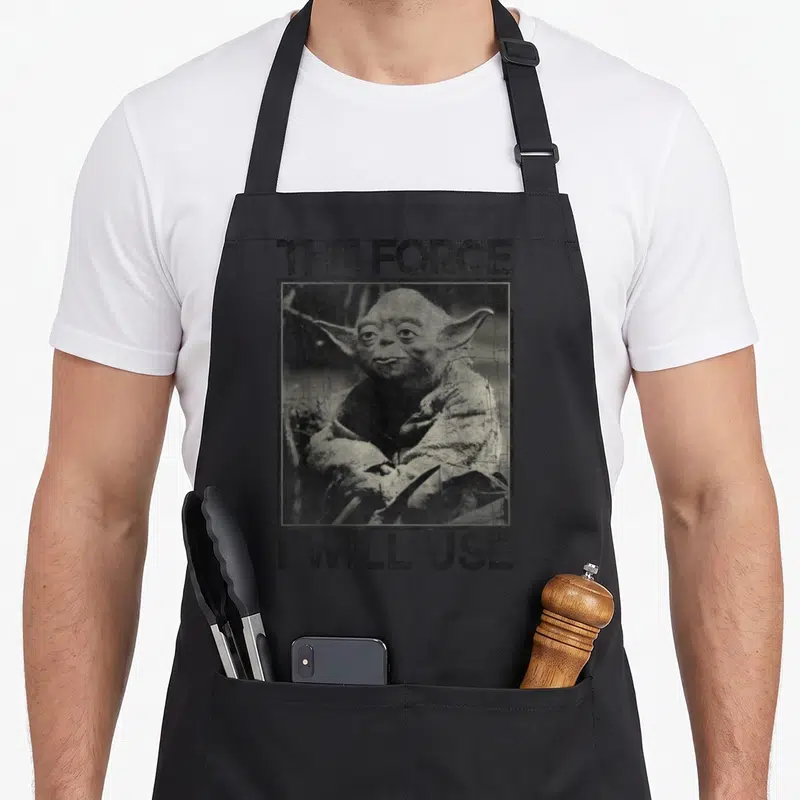 Tablier de cuisine noir avec portrait vintage de Yoda et texte The Force I Will Use imprimé en gras.