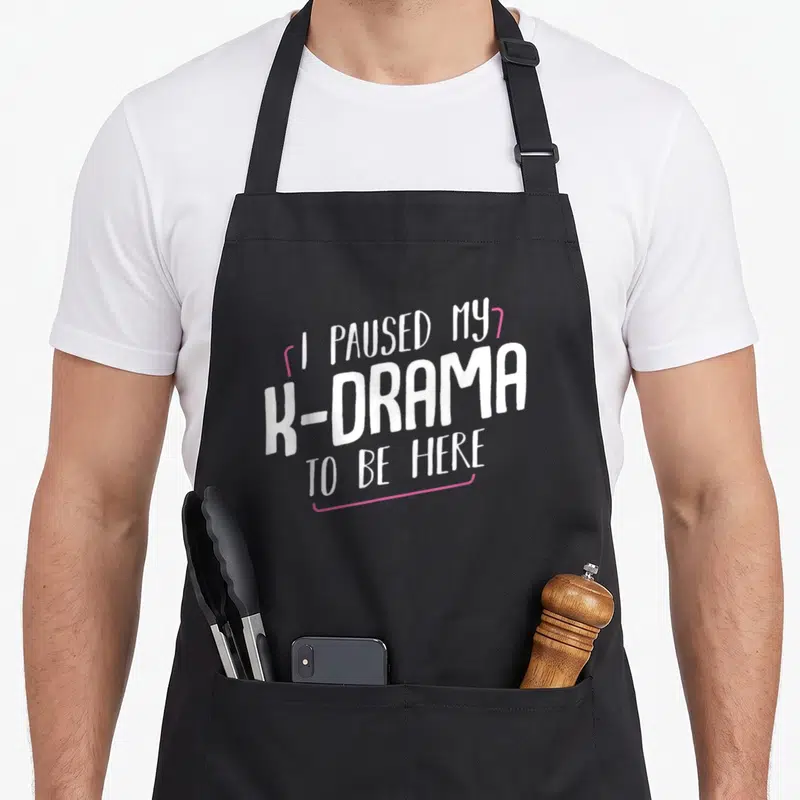 Tablier de cuisine noir avec l'inscription blanche et rose I Paused My K-Drama To Be Here.
