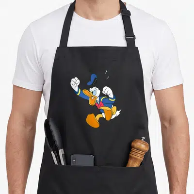 Tablier de cuisine noir avec Donald Duck en train de sauter de colère, poings serrés et chapeau qui s'envole.
