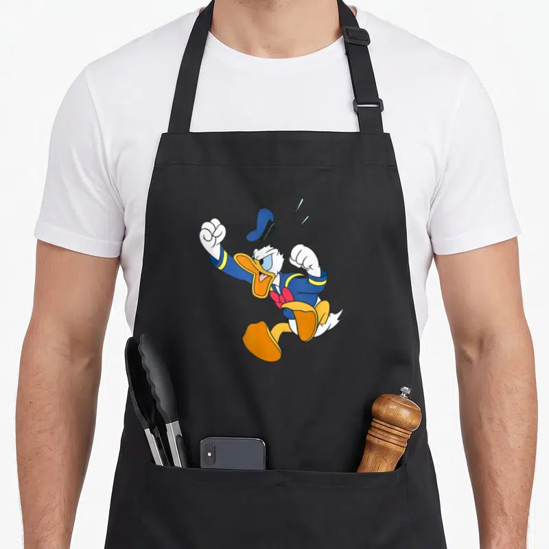 Tablier de cuisine noir avec Donald Duck en train de sauter de colère, poings serrés et chapeau qui s'envole.