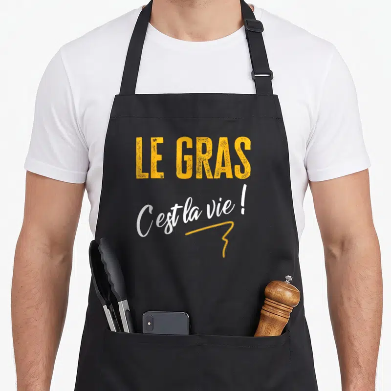 Tablier de cuisine noir avec le texte Le Gras C'est la vie en orange et blanc, style typographique décontracté.