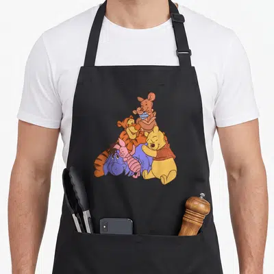 Tablier de cuisine noir avec Winnie l'Ourson, Tigger, Kanga, Roo, Éeyore et Piglet en groupe.